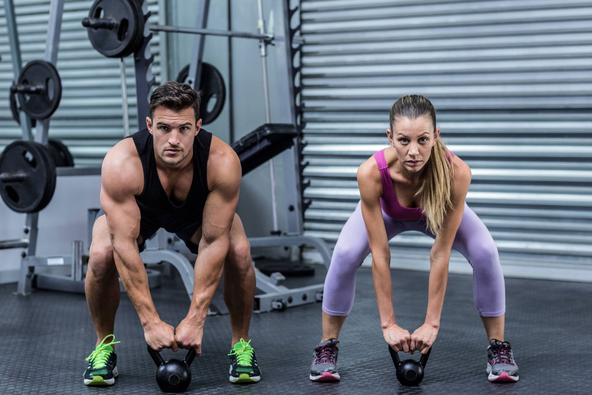 Twee sporters met kettlebells in de krachtruimte